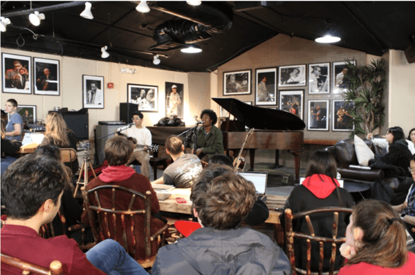 A group of students watching a jazz pianist perform at the CoHo
