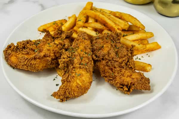 Crispy golden fried chicken tenders served with seasoned French fries on a white plate.