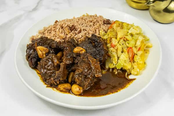 Tender oxtails in rich brown gravy served with rice and peas, and sautéed cabbage with bell peppers.