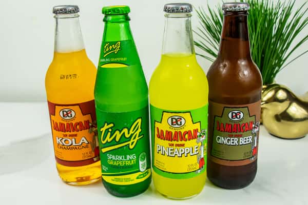 Four Caribbean soft drinks on display: DG Jamaican Kola Champagne, Ting Sparkling Grapefruit, Pineapple, and Ginger Beer.