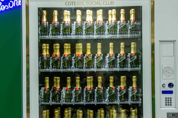 Champagne vending machine labeled "Coterie Social Club" stocked with Moët & Chandon bottles in numbered slots.