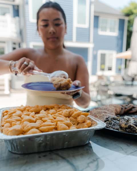Person scooping macaroni and cheese onto a plate