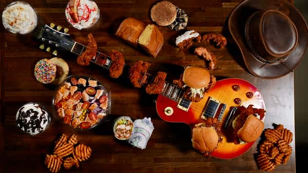 A flatlay of chicken entrees and sides on a table with a guitar
