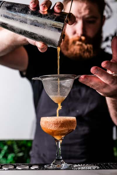 Bartender filtering a cocktail
