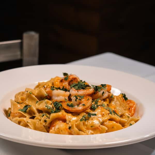 homemade pasta, perfectly al dente, coated in a rich, traditional Italian sauce and topped with succulent shrimp