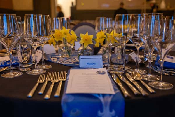 Refined table setting with polished silverware, wine glasses, and floral centerpieces, prepared for an elegant restaurant dinner or special occasion.