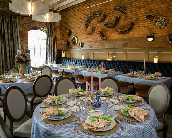 Stylishly set banquet tables with candles, floral accents, and coordinated linens in an intimate restaurant space designed for private dining events.