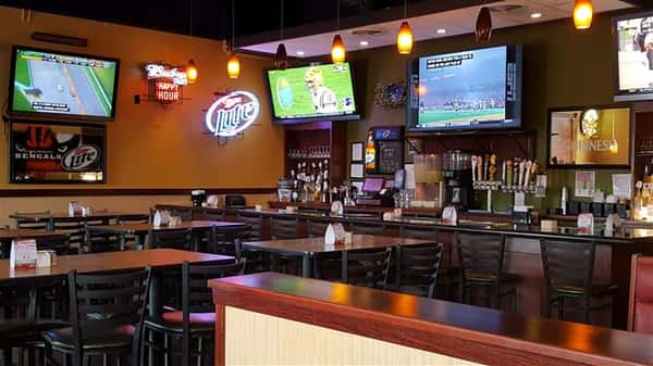 Televisions on the wall with tables and chairs