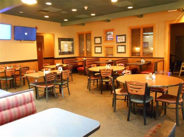 Interior of restaurant with brown walls and green ceilings and tables and chairs