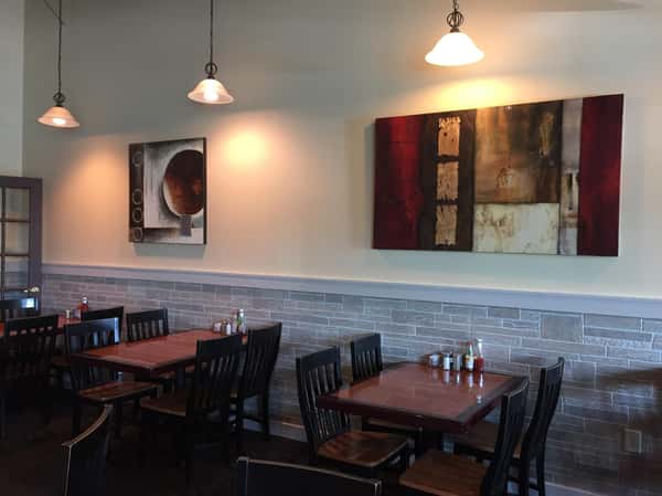 Interior dining area with wooden tables and chairs and abstract art on the walls