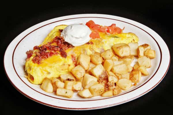 Omelet with crumbled bacon and diced tomatoes with sour cream and breakfast potatoes