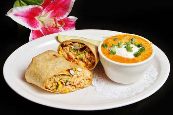 Chicken burrito with rice, corn and beans and a side of cheese sauce with sour cream and green onions