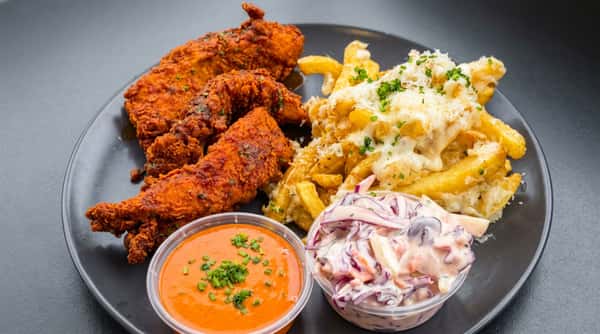 Crispy fried chicken tenders with cheesy loaded fries, creamy slaw, and spicy dipping sauce