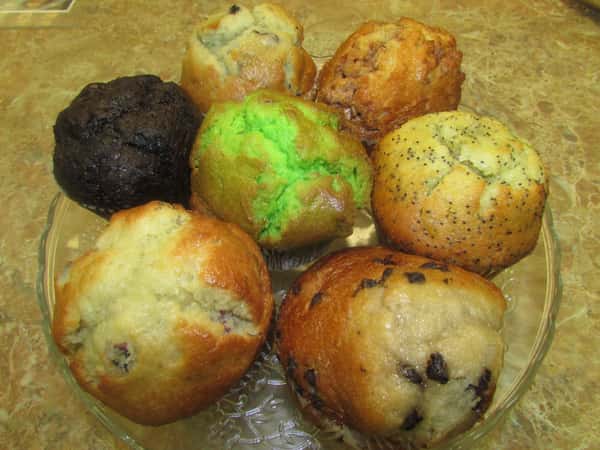 Variety of seven muffins inclusing chocolate chip, pistachio, chocolate, and poppy seed.