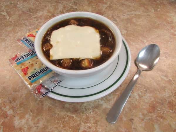 Soup topped with melted cheese with two Premium brand saltine crackers