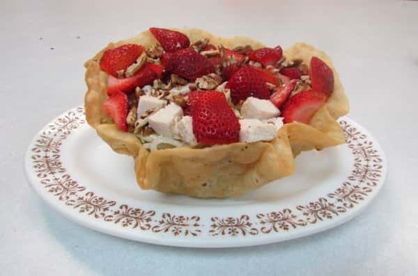 Tortilla bowl filled with shredded lettuce, pecans and strawberries