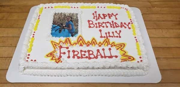 A cake decorated with a photo of a girl that says happy birthday lilly
