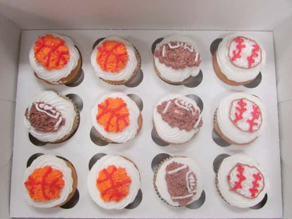 White frosted cupcakes topped with frosted footballs, baseballs and basketballs