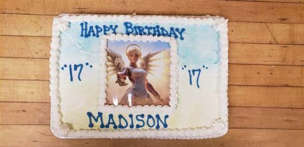 A rectangle cake that has a picture of an angel character in the center that says Happy Birthday Madison
