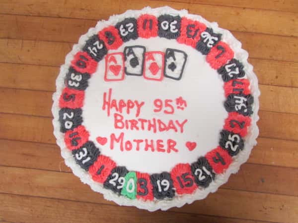 Poker themed cake decorated like a roulette wheel readin "Happy 95th Birthday Mother"