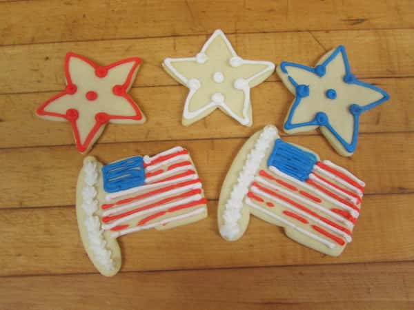 Three re, white and blue star shaped cookies with two cookies that resemble the american flag