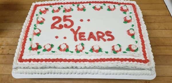 Rectangle cake that says 25 years with a border of red and white frosted flowers