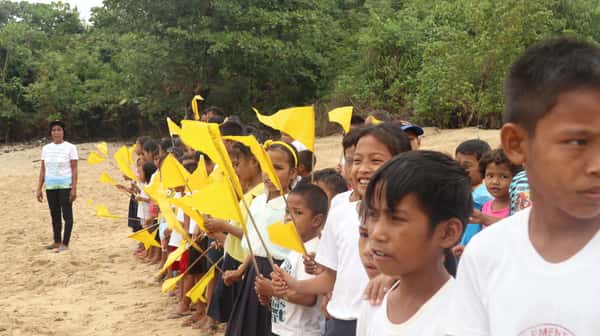 Children by the Beach holding yellow flags