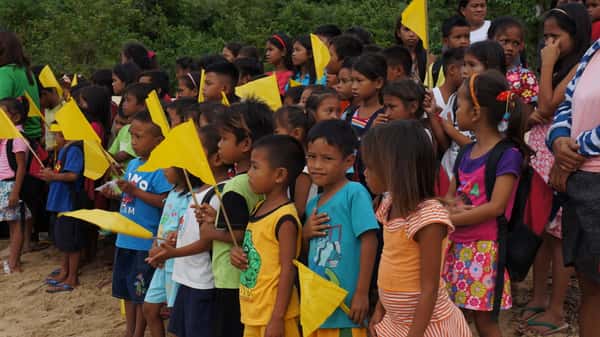 Children by the Beach holding yellow flags