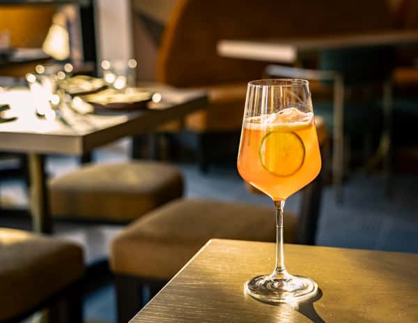 Refreshing citrus cocktail with lime garnish served in a wine glass inside a modern upscale restaurant