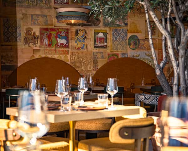 Upscale restaurant interior with artistic wall murals, warm lighting, and intimate dining tables