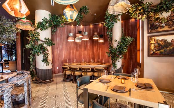 Modern restaurant interior with lush greenery, designer pendant lights, and contemporary dining tables