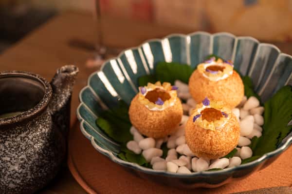 Crispy pani puri appetizers served with savory sauce and edible flower garnish in a modern Indian restaurant