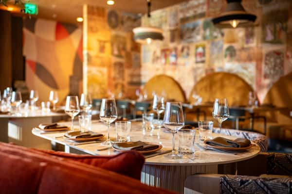 Modern restaurant dining area with marble tables, wine glasses, and warm ambient lighting