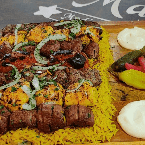 Grilled beef and chicken kabobs served over saffron rice with roasted tomato, onions, pickles, and creamy garlic sauce on the side.