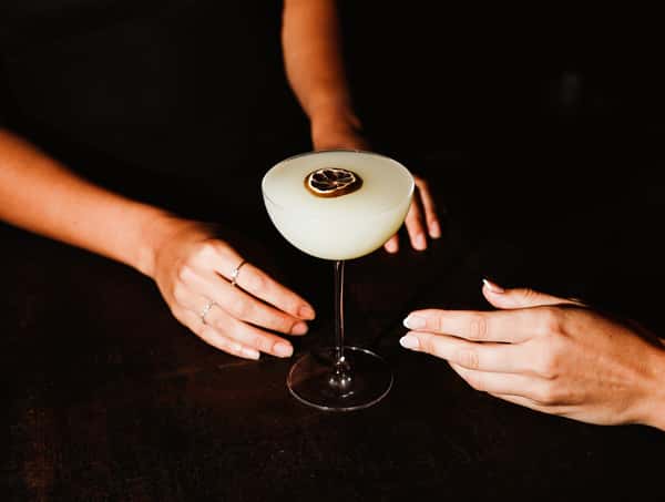 Two young women reaching for the same cocktail