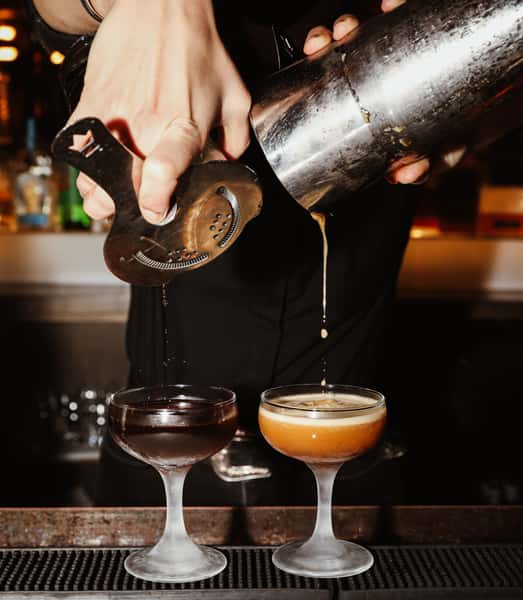 Bartender expertly crafting two cocktails simultaneously