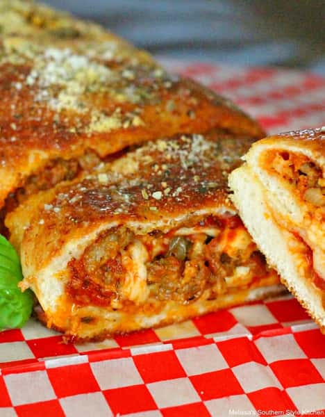Baked stromboli filled with meat, cheese, and marinara, sliced open to show the filling.