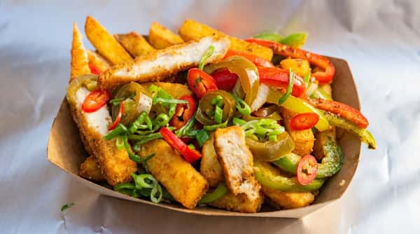 Fries with breaded chicken strips, sliced red and green bell peppers, jalapeños, and green onions in a cardboard tray.