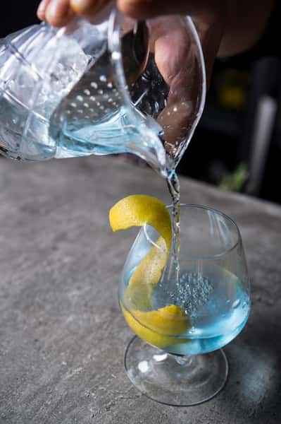 Server pouring water with lemon