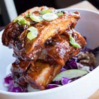 a pile of ribs on top of cabbage in a bowl