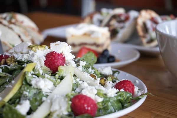 a salad with sliced apples, cheese crumbles, and berries on top
