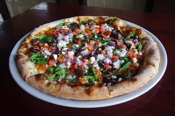 a salad pizza with onions, tomatoes, letuce, cheese, and beans.
