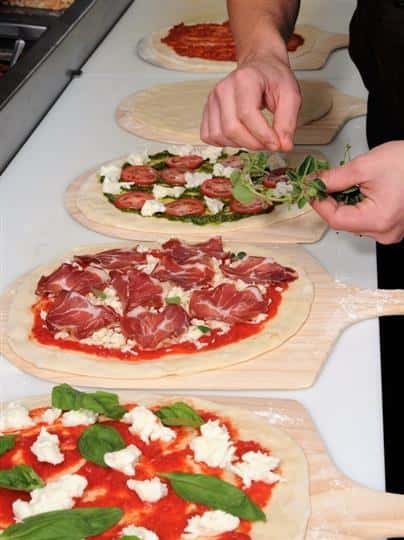 3 raw pizzas being prepared on pizza paddles