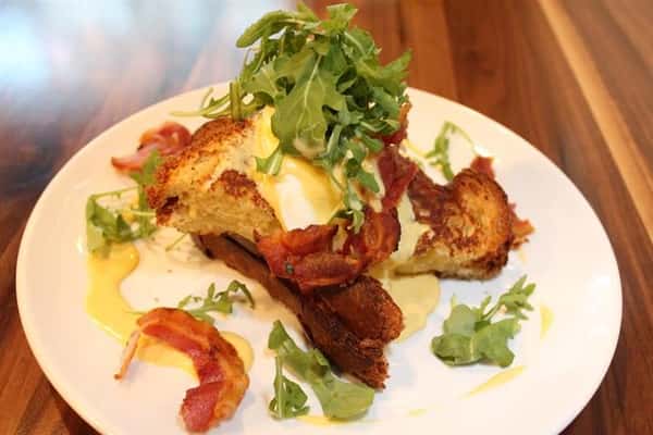 toast with a yellow sauce, lettuce and bacon on top