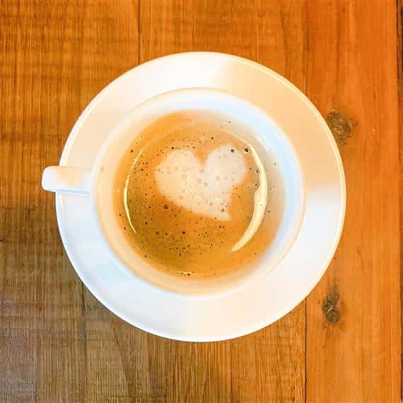 coffe mug with hot coffee and foam shaped as a heart