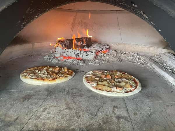 wood fired oven cooking two pizzas