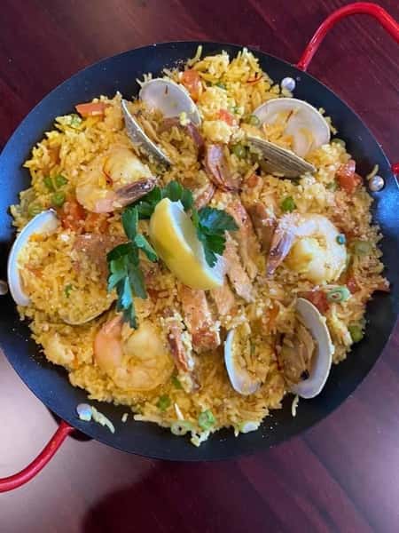SEAFOOD PAELLA: mussles, clams, shrimp, chicken, chorizo, english peas, & roasted tomatoes over saffron rice