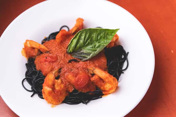 Black squid ink pasta topped with shrimp, mussels, tomato sauce, and fresh basil at Pasta Lovers Trattoria.