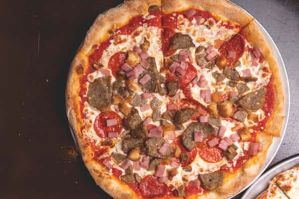 Freshly baked Italian pizza topped with pepperoni, sausage, melted mozzarella cheese, and tomato sauce at Pasta Lovers Trattoria in Midtown Manhattan, NYC.