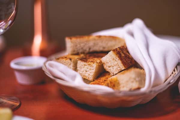 Basket of warm Italian bread served with a white napkin on a restaurant table at Pasta Lovers Trattoria.